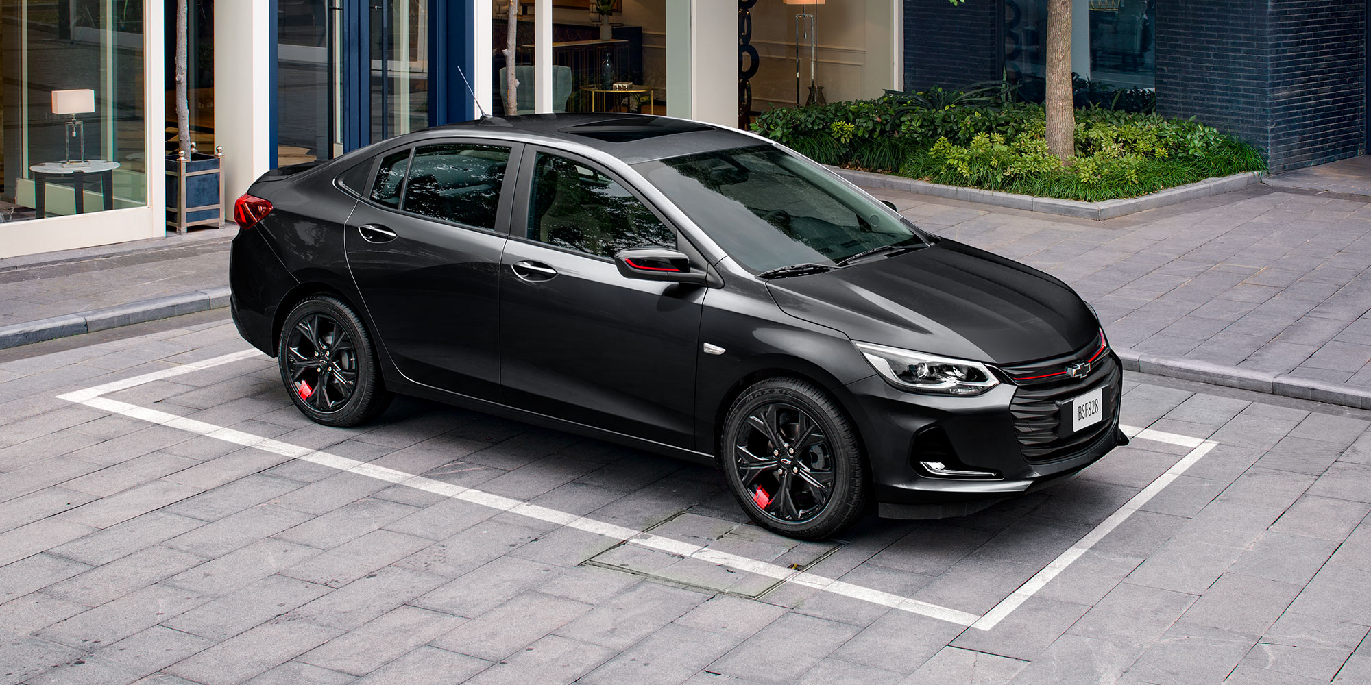 Chevrolet Onix 2025, sedán deportivo equipado con rines negros con detalle en rojo y manijas exteriores al color de la carrocería
